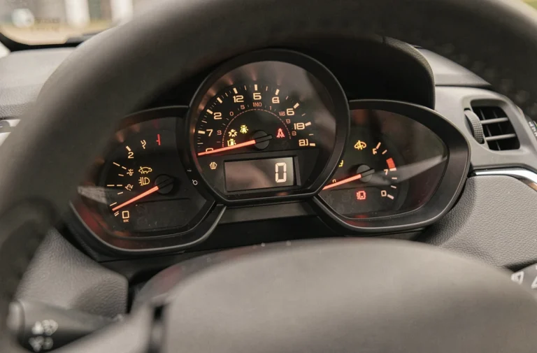 Gros plan sur les voyants du tableau de bord d'une Peugeot 208 essence allumés en rouge et orange